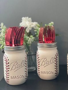 three mason jars with red plastic forks and silverware in them are sitting on a table