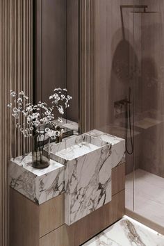 an elegant bathroom with marble counter tops and white flowers in vases on the sink