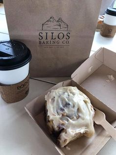 a pastry in a box next to a cup of coffee