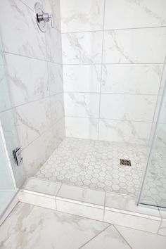 a white tiled shower stall with hexagonal tiles on the floor and walls,