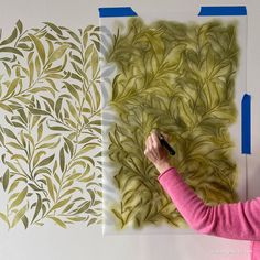 a woman is drawing leaves on a piece of paper