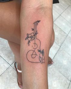 a woman's leg with a tattoo on it that has an image of a guitar and flowers