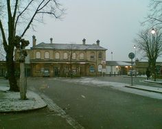 an empty street in front of a building with snow on the ground and bare trees