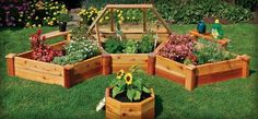 several wooden planters in the grass with flowers and plants growing out of one end