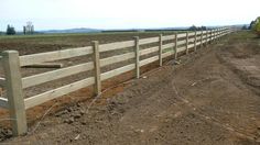 a wooden fence in the middle of a dirt field