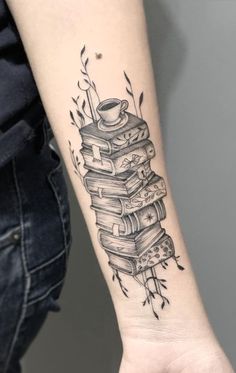 a woman's arm with a stack of books tattoo on it