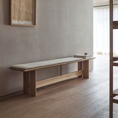 a wooden bench sitting in the middle of a living room next to a painting on the wall