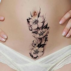 a pregnant woman's stomach with flowers on the side and behind her belly tattoo