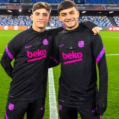 two men standing next to each other in front of a soccer field with the words beko on it