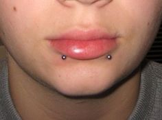 a close up view of a person's nose with piercings on their lips