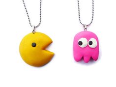 two necklaces made to look like pacman and alien heads, one is yellow and the other is pink