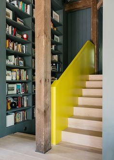 there is a yellow stair case next to the bookshelves