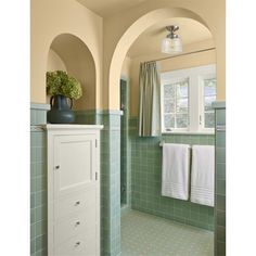 a green tiled bathroom with an arched doorway