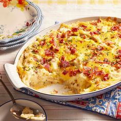 a casserole dish with bacon and cheese in it on a table next to other dishes