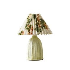 a lamp with a flowered shade on the top and bottom, sitting on a white surface