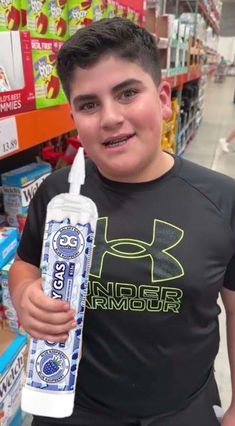 a young boy holding up a toothbrush in a store