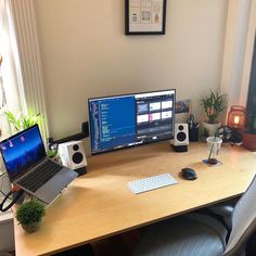 a computer desk with two monitors and a laptop on it in front of a window