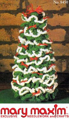 a crocheted christmas tree with red and white ribbons on it's base