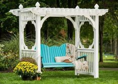 a blue and white bench sitting on top of a green grass covered park area next to flowers