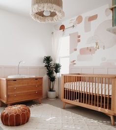 a baby's room with two cribs, a dresser and a potted plant