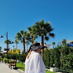 a man wearing a pirate hat walking down a sidewalk with palm trees in the background