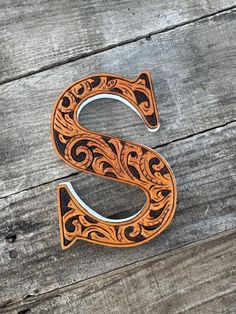 the letter s is made out of wood and has an intricately carved design on it