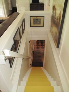 the stairs are painted yellow and white with pictures on each side, along with framed art