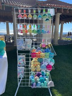 a rack filled with stuffed animals on top of a grass covered field next to a pavilion