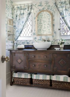 a bathroom with blue and white wallpaper, a sink and window in the corner