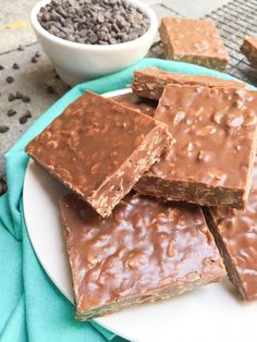 chocolate fudge bars on a white plate next to a bowl of brownie chips