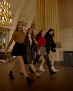 four young women are walking in a large room