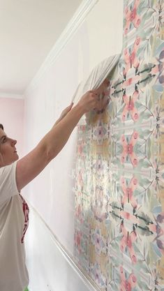 a woman is painting flowers on the wall