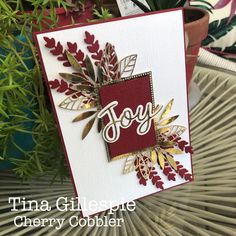 a close up of a card on a table with plants in the background and a potted plant behind it