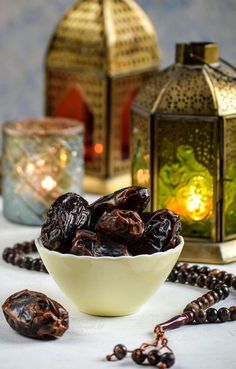 a bowl filled with raisins sitting on top of a table next to a lantern