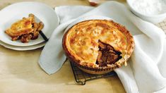 there is a pie on the table next to two plates with pastries in it