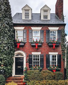 a brick house with black shutters and red bows