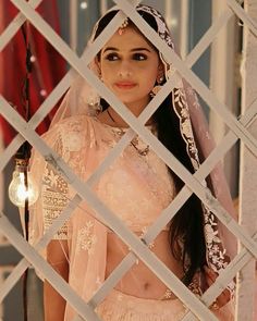 a woman in a bridal outfit looking through a fence