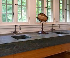 a kitchen with double sinks and marble counter tops in front of two windowed windows