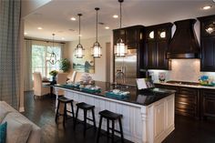 a large kitchen with dark wood cabinets and white counter tops, along with bar stools