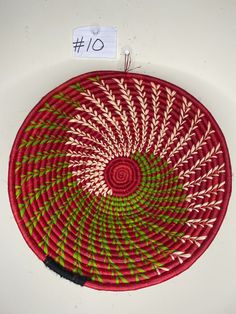 a red and green woven basket hanging on a wall next to a price tag with the number 10