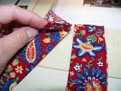 a person is using a sewing machine to sew on a red flowered tie