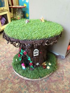 a cake made to look like a tree stump with a house in the grass on top