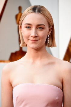 a woman with blonde hair wearing a pink strapless dress at an oscars event