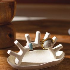 a white ring holder with two rings on it and a wooden table in the background