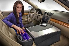 a woman sitting in the driver's seat of a car with a cooler on it