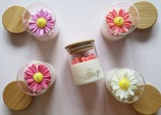 small jars filled with pink and yellow flowers on top of a white table covered in wooden circles