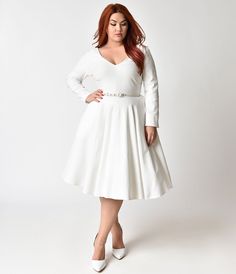 a woman in a white dress posing for the camera with her hands on her hips