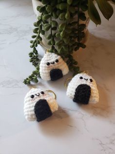 three crocheted sheep keychains sitting next to a potted plant