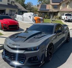 a grey chevrolet camaro is parked in front of a house with solar panels on the roof