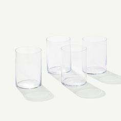 four clear glass tumblers sitting on top of each other in front of a white background